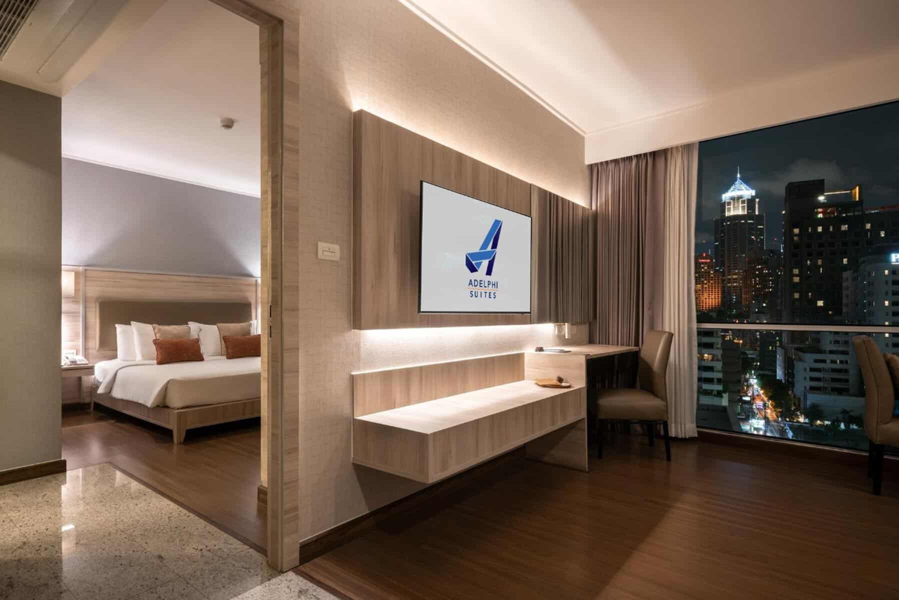 A one-bedroom suite at Adelphi Suites Bangkok with a separate bedroom, living area and night view over Sukhumvit