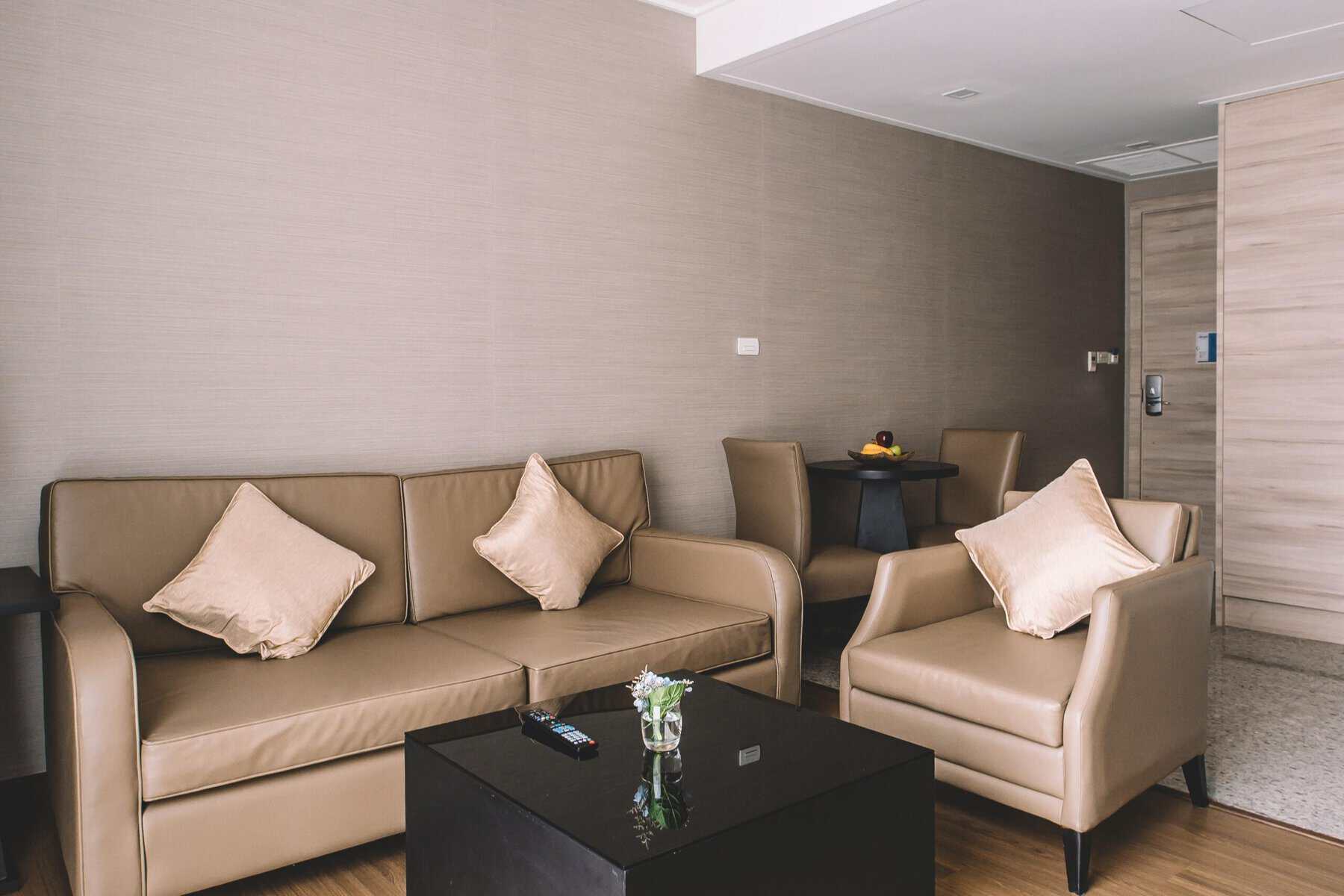The living area of an Adelphi Suites Bangkok suite, with a full sofa and armchairs separate from the bedroom