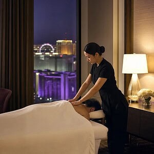 Masseuse giving an outcall massage in a Bangkok hotel room with a city view