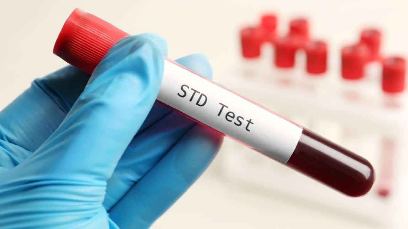 STD test blood sample vial held by a gloved hand at a clinic