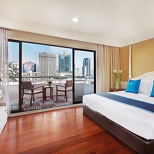 A Centre Point Sukhumvit 10 balcony suite, sliding doors open onto a furnished private balcony with a table and chairs over the city