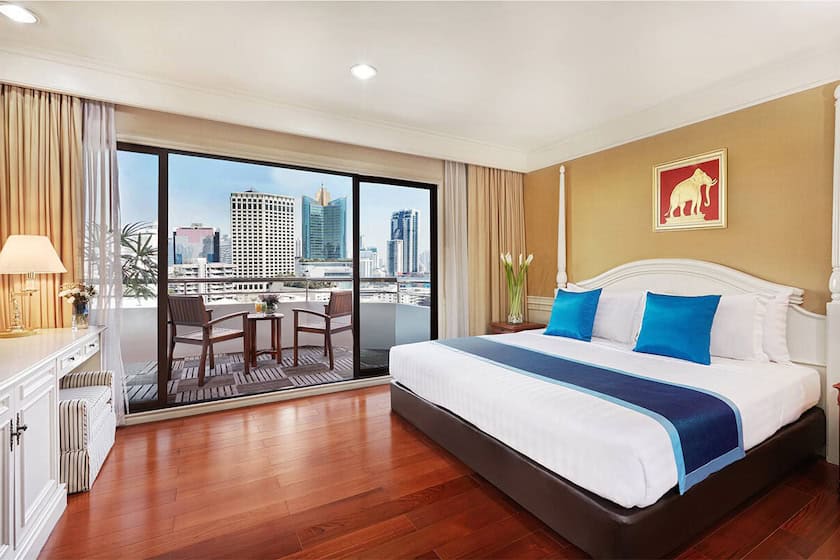 A Centre Point Sukhumvit 10 balcony suite, sliding doors open onto a furnished private balcony with a table and chairs over the city