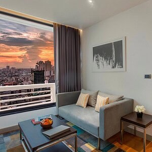 The living room of a Fraser Suites Sukhumvit penthouse on Soi 11, with a full sofa, coffee table and the bedroom through the opening