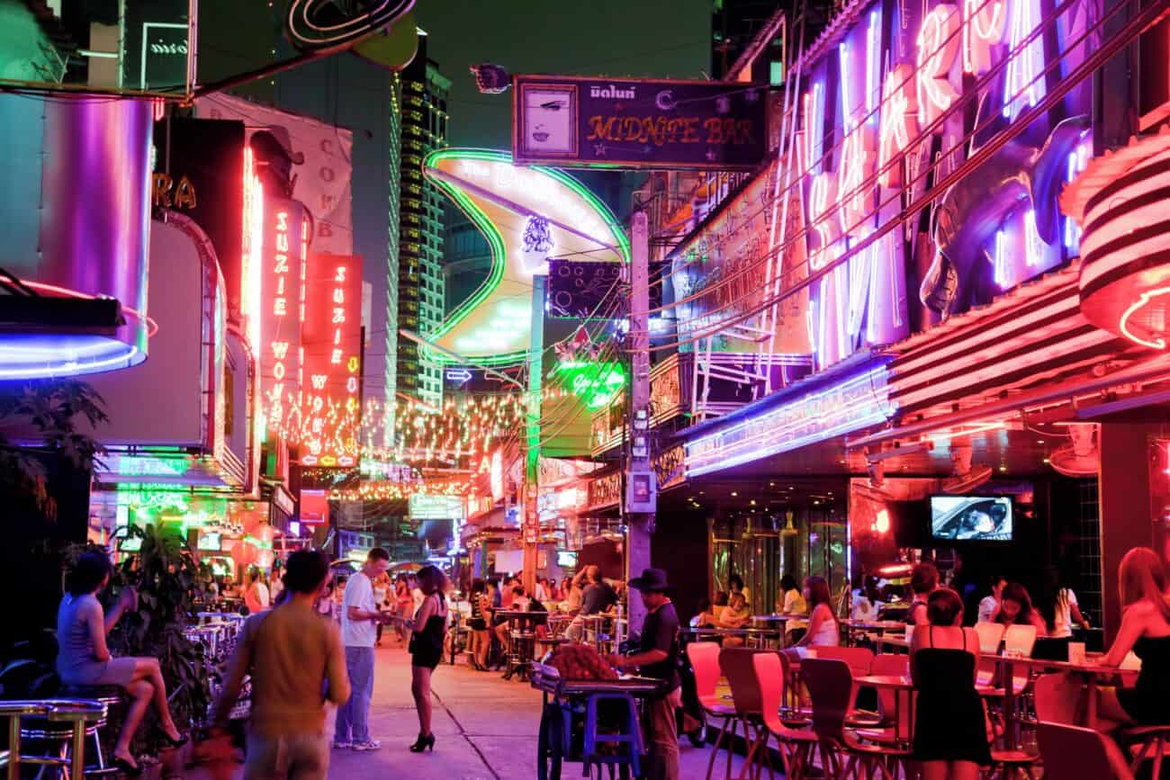 Soi Cowboy at night between Sukhumvit Soi 21 and 23, neon bar signs along the strip