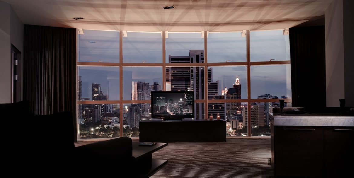Night view from the S31 Sukhumvit Panorama Suite, showing the curved window wall, lounge seating and marble bar counter