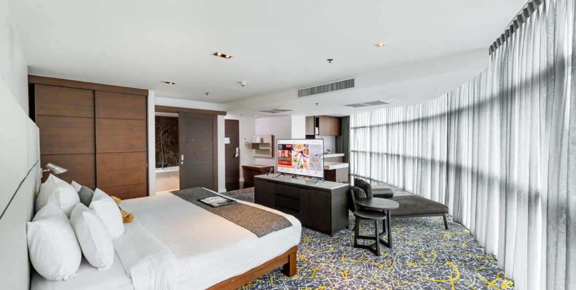 S31 Sukhumvit suite layout: king bed, separate lounge seating and the curved window wall