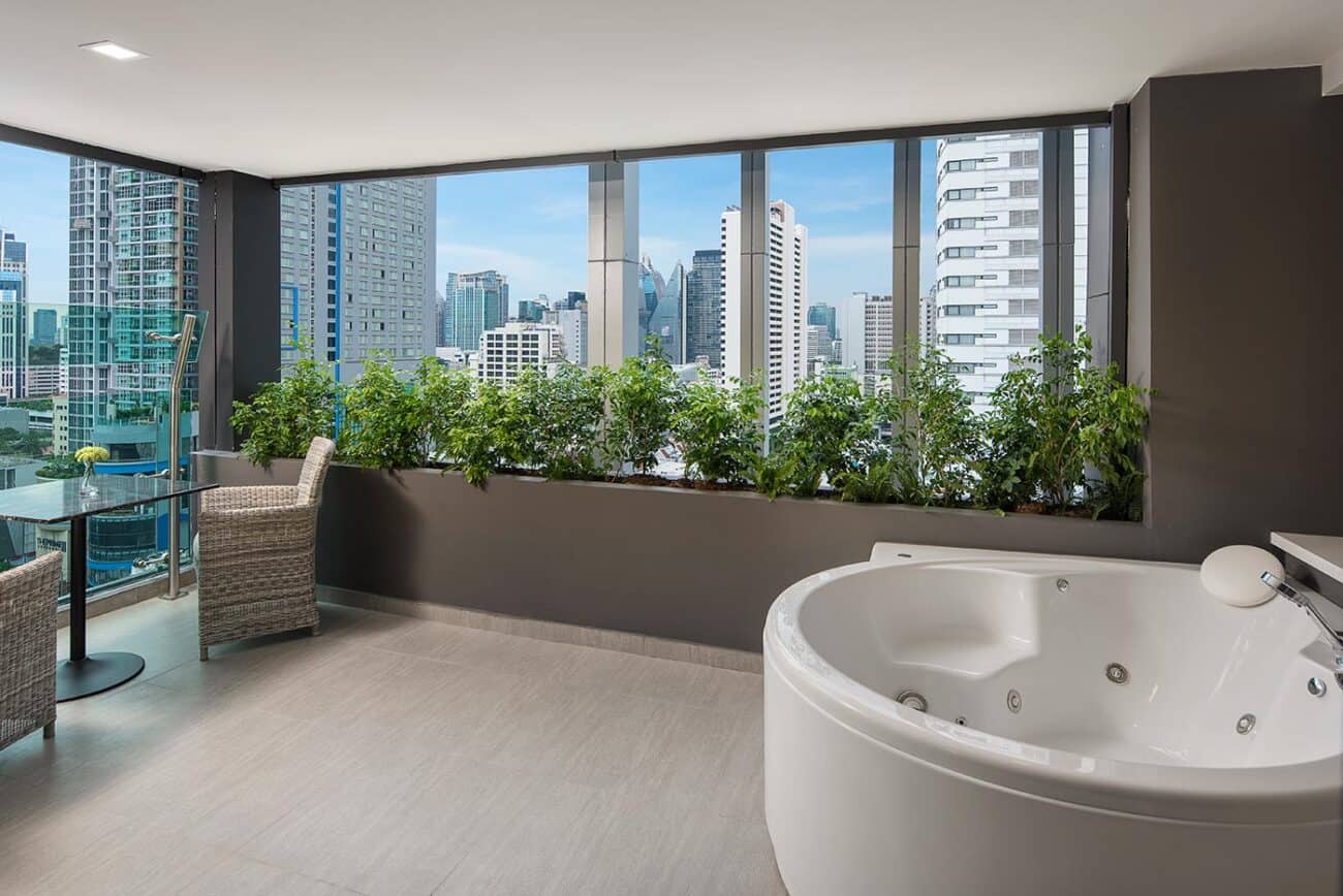 The Jacuzzi Suite with Balcony at Solitaire Bangkok Sukhumvit 11, a jetted round tub on the private balcony with a skyline view