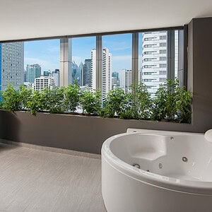 The Jacuzzi Suite with Balcony at Solitaire Bangkok Sukhumvit 11, a jetted round tub on the private balcony with a skyline view