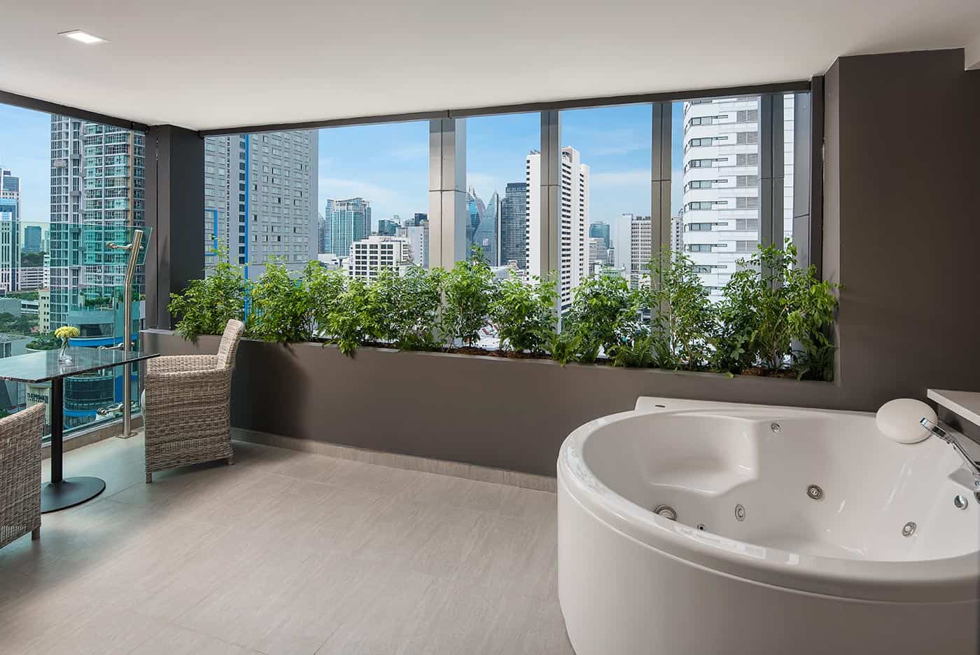 The Jacuzzi Suite with Balcony at Solitaire Bangkok Sukhumvit 11, a jetted round tub on the private balcony with a skyline view