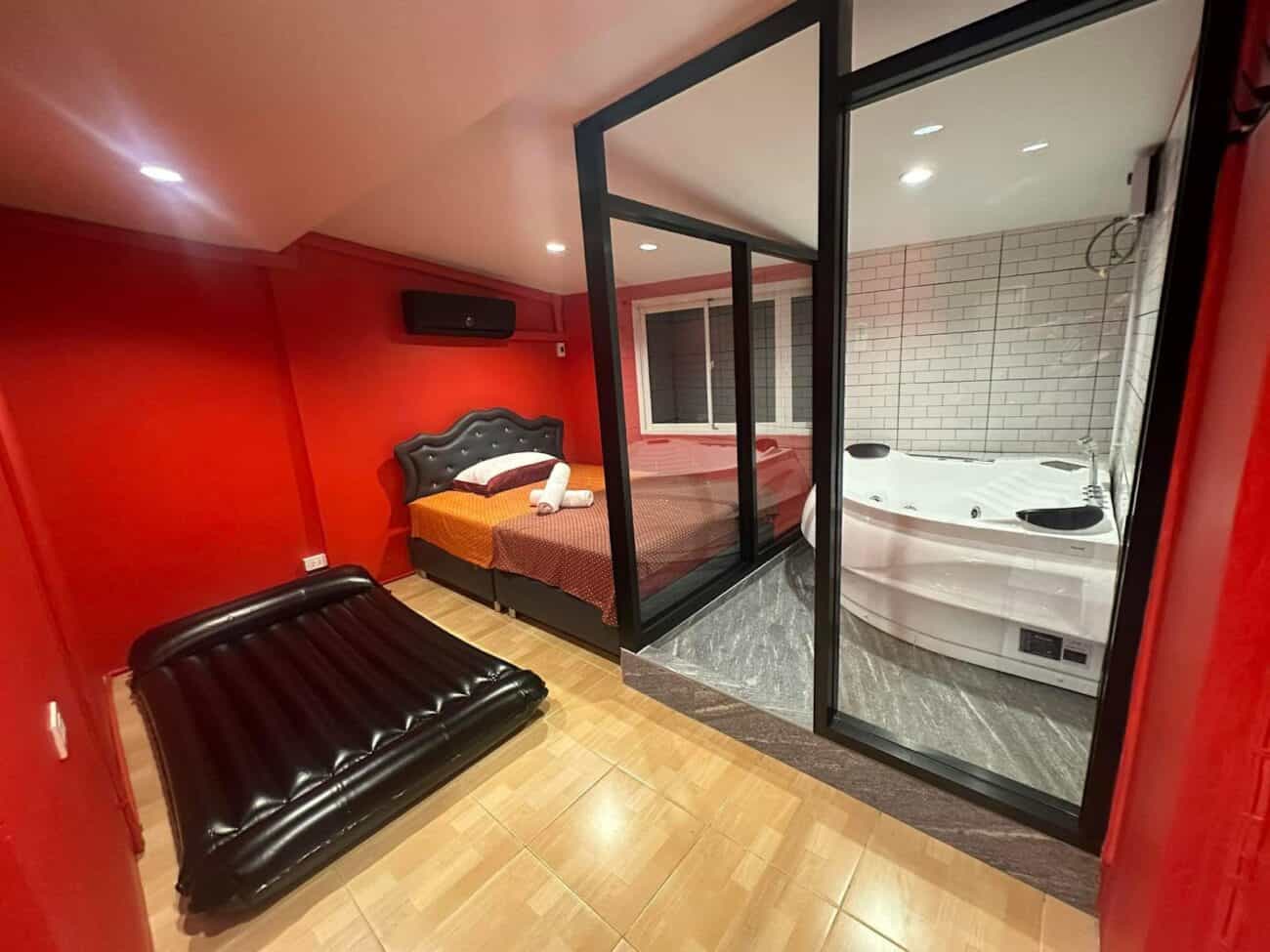 Red room at Cherry Massage, Sukhumvit Soi 22, with a nuru mattress, bed and glass-walled jacuzzi