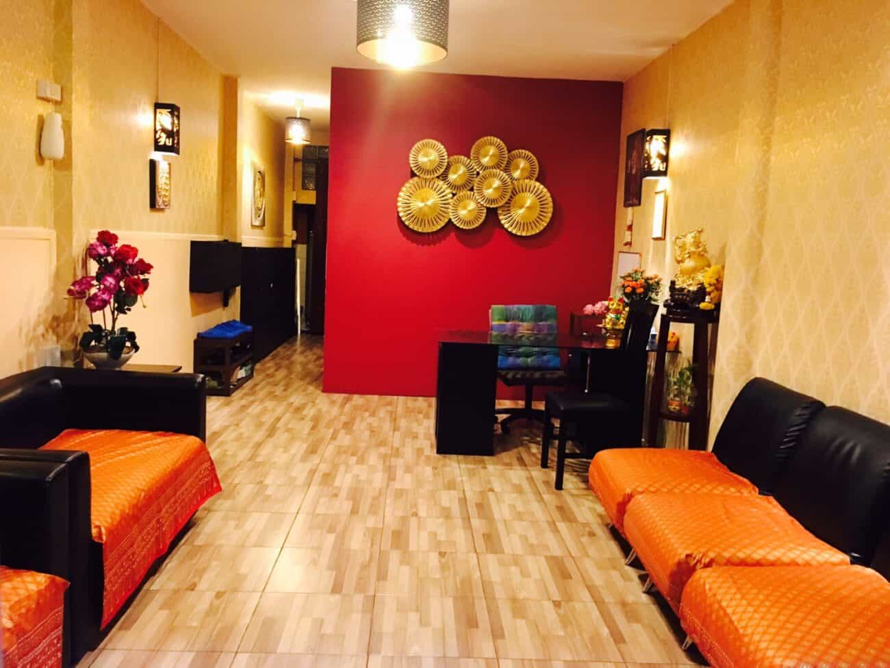 Reception lounge with orange sofas and a red feature wall at Paradise Massage, Sukhumvit Soi 22, Bangkok