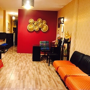 Reception lounge with orange sofas and a red feature wall at Paradise Massage, Sukhumvit Soi 22, Bangkok