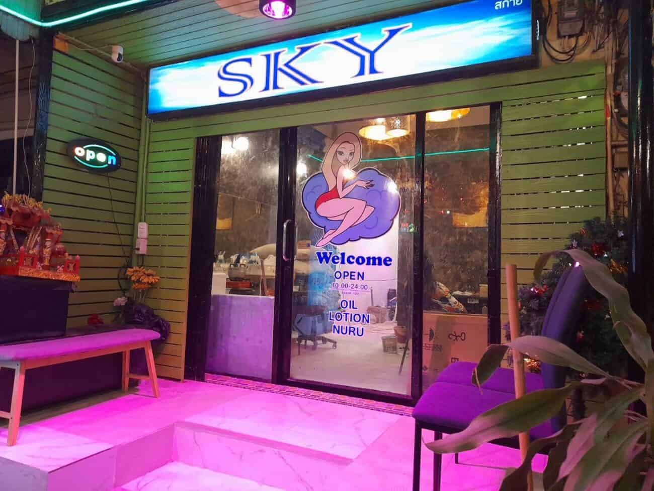Sky Massage storefront on Sukhumvit Road, Bangkok, at night, with oil, lotion and nuru listed on the door