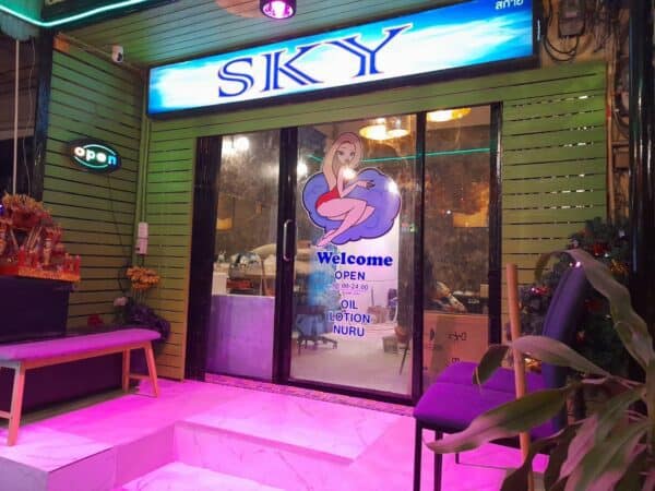 Sky Massage storefront on Sukhumvit Road, Bangkok, at night, with oil, lotion and nuru listed on the door