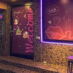 Neon-lit entrance of Vovo on Sukhumvit Soi 33, with the Vovo lips logo and Welcome door