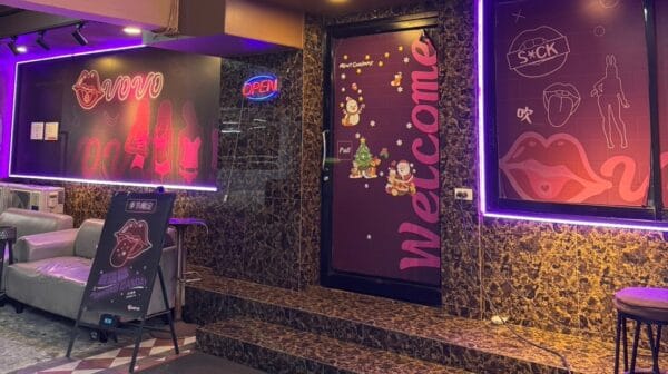 Neon-lit entrance of Vovo on Sukhumvit Soi 33, with the Vovo lips logo and Welcome door